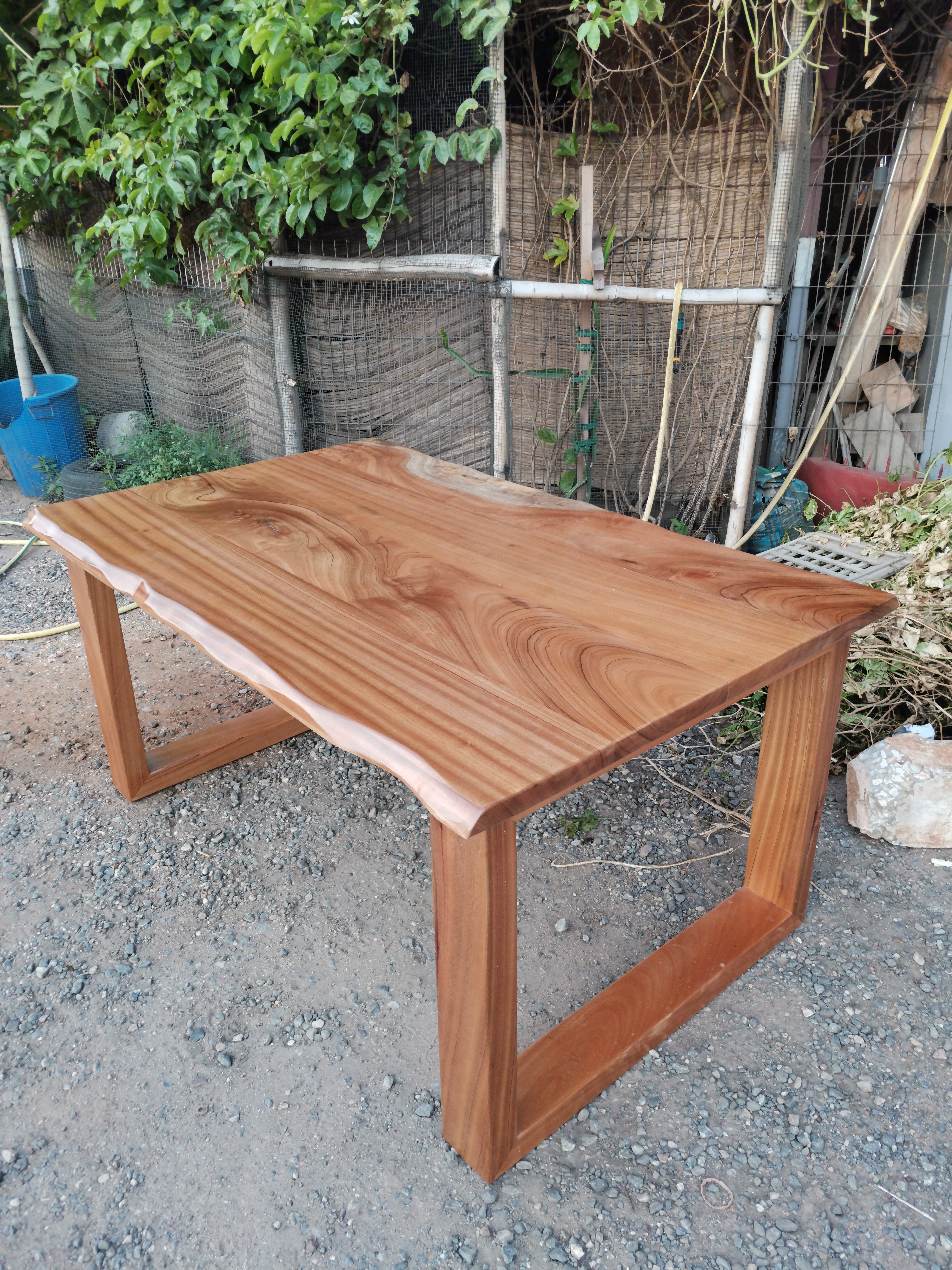 Afromosia live-edge dining table outdoors — Ridge, Accra